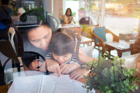 happy family mother and daughter read a book at cafe