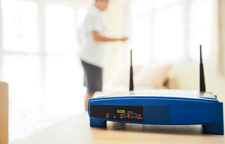 closeup of a wireless router and a young man using Laptop and notebook computers on living room at home with a window in the backgroundの写真素材