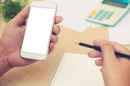 Businessman's hands holding and use mobile phone on on office tableの写真素材