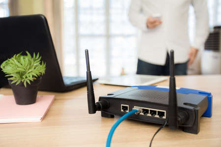 closeup of a wireless router and a man using smartphone on living room at home ofiiceの写真素材