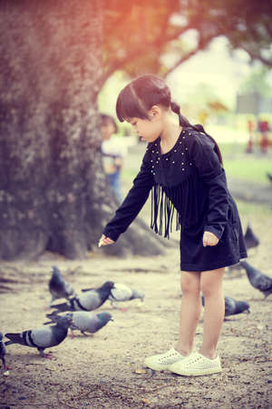 Little girl feeding  pigeons seeds.の写真素材