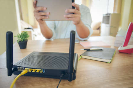 closeup of a wireless router and a man using  Tablet on living room at home ofiiceの写真素材