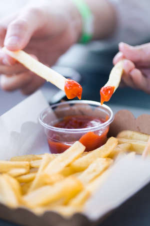 hand Mother and daughter holding serrated french fries dip to tomato sauceの写真素材