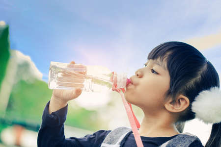school kids drink water from a bottle against the background sky.の写真素材