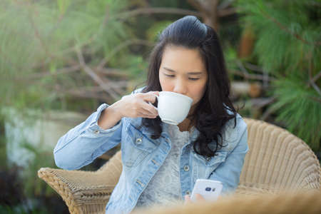 businesswoman reading news or texting sms on smartphone while drinking coffee on break from workの写真素材