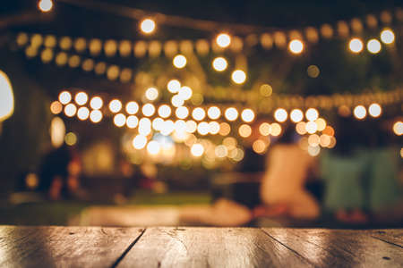 Image of wooden table in front of abstract blurred restaurant lights backgroundの写真素材