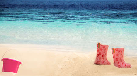 Colorful  Boots for children in the sand on a beach in the summerの写真素材