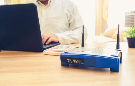 closeup of a wireless router and a man using Laptop and notebook computers on living room at home ofiiceの写真素材