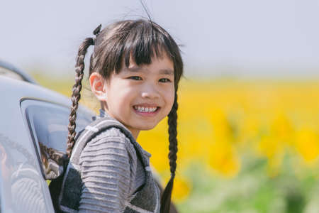 portrait asia children smiling sitting in the car looking out windows, ready for vacation tripの写真素材