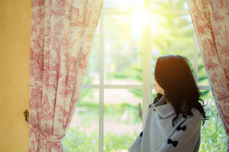 girl opening curtains in  living-roomの写真素材
