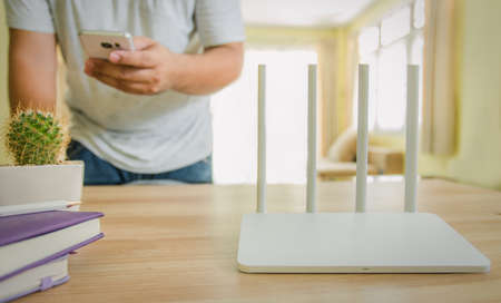 closeup of a wireless router and a man using smartphone on living room at home ofiiceの写真素材