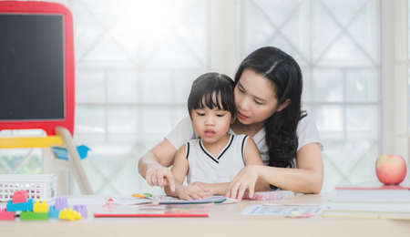 happy family mother and daughter read a book at homeの写真素材