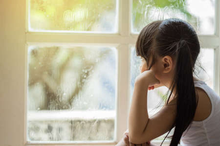 Depressed Little girl  near window at home, closeupの写真素材