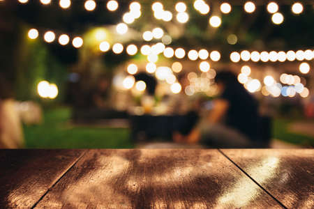 Image of wooden table in front of abstract blurred restaurant lights backgroundの写真素材