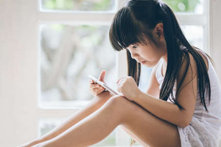 Asian girl are using the smart phone on she near windowの写真素材