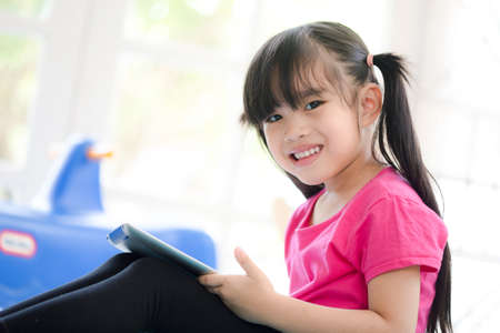 cute girl enjoy to play internet on a tablet computer at home;