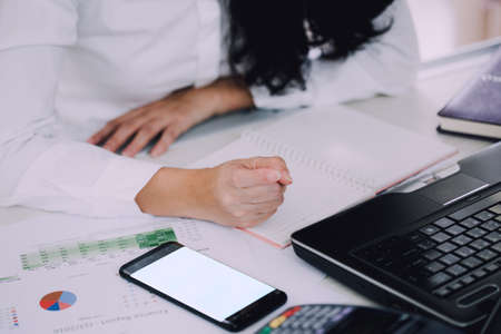 Woman with laptop and mobile phone working in office interiorの写真素材