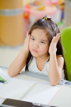 Decent school child. holding her head with a hand and reading a bookの写真素材