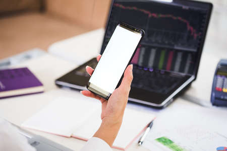 woman working in office interior on pc holding smartphone.Office person using mobile phone and laptopの写真素材