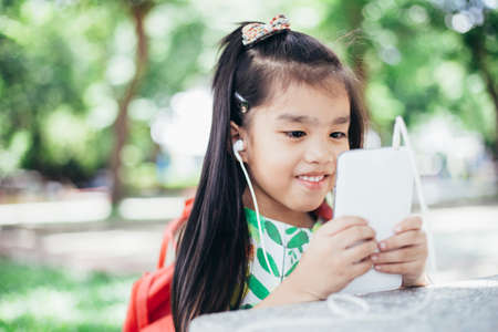 Happy Asian girl playing game on mobile phoneの写真素材