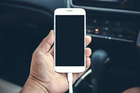 Man sitting in the car and holding a smartphone with isolated screen