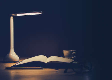 Office desk with Led lamp,cup of coffee and paperwork stackの写真素材