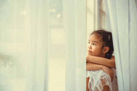 Depressed Little girl near windows at homeの写真素材