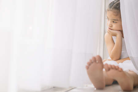 Depressed Little girl near windows at homeの写真素材