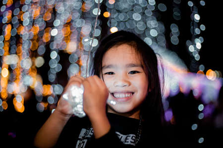 Happy children Holding a light on a New Year's Eve.Street Night Scene with Christmas Lightsの写真素材