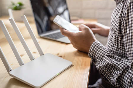 closeup of a wireless router and a man using smartphone on living room at home ofiiceの写真素材