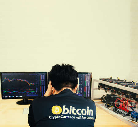 a man hanging his head in front of a crashing bitcoin  stock chartの写真素材
