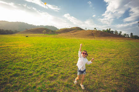 little girl running with kite happy and smiling on summer fieldの写真素材