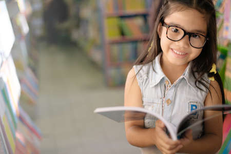 Portrait  Asian child  holding open textbook in hands in book storeの写真素材