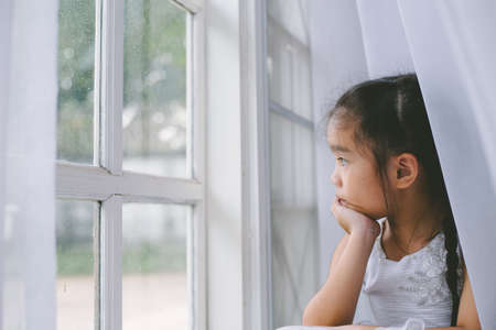 Depressed Asian child  near window at home, closeupの写真素材