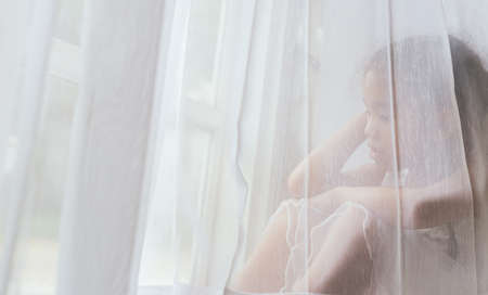 Depressed Asian child  near window at home, closeupの写真素材