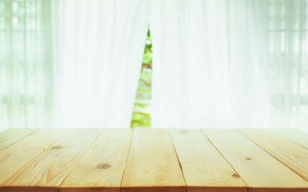 wood table top on blur of curtain with window view green from tree garden background.can be used for...