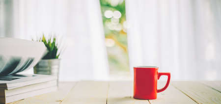 cup of coffee on wood table top and blur of curtain with window  backgroundの写真素材