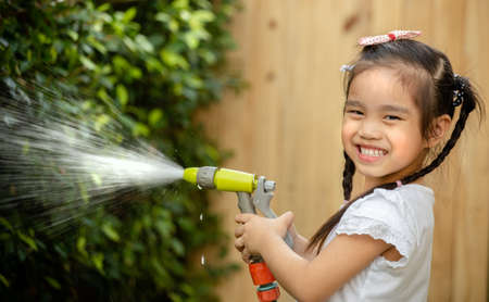 Happy little asia girl having fun in the garden ,Working watering gardenの写真素材