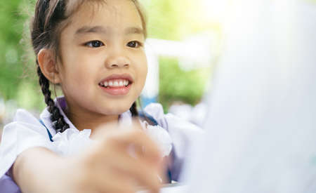 Cute  asian girl  reading a book and smiling teeth  white  whileの写真素材