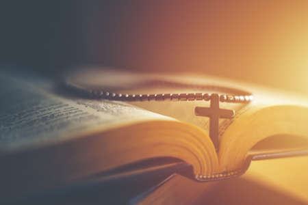 Closeup of wooden Christian cross necklace next to holy Bibleの写真素材