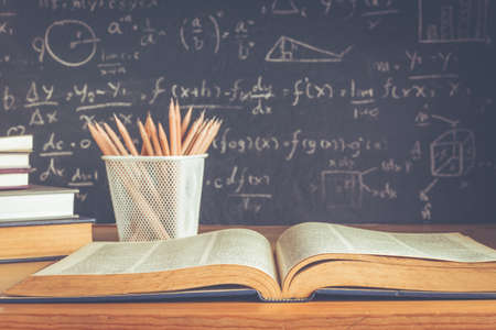 School books on desk formulas and Physics inscription on the blackboard , education conceptの写真素材