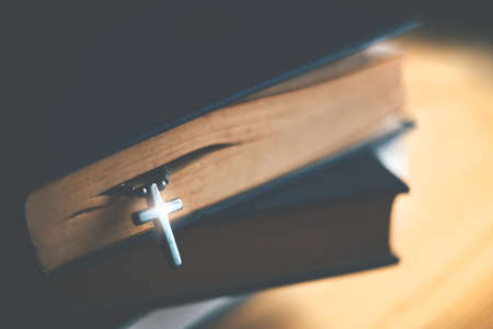 Closeup of wooden Christian cross necklace next to holy Bibleの写真素材