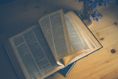 Open book on wood desk in the library room with blurred focus for education backgroundの写真素材