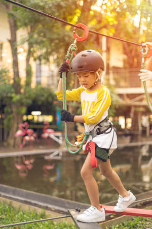 Happy school girl enjoying activity in a adventure parkの写真素材