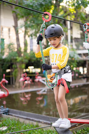 Happy school girl enjoying activity in a adventure parkの写真素材