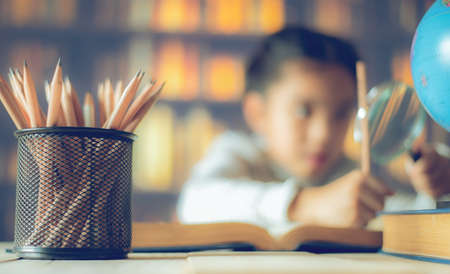 pencils on a wooden table and  asian child  industrious  is sitting at a desk 
 background. Educational backgroundの写真素材