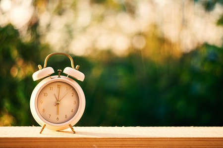 Clock on wood in the morning, blurred nature backgroundの写真素材