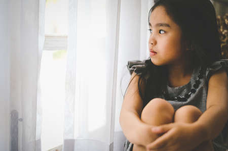 Depressed Little girl near window at home, closeupの写真素材
