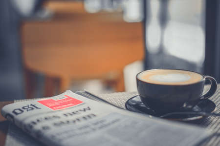 A cup of coffee and a newspaper of coffee on a wooden tableの写真素材