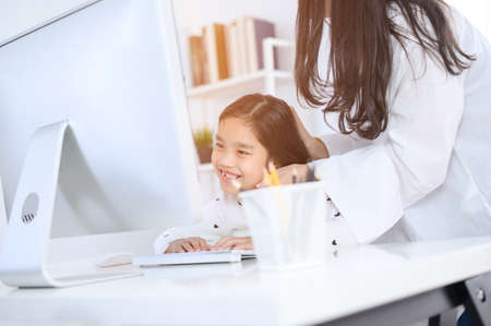 happy Little girl looking at computer with her motherの写真素材